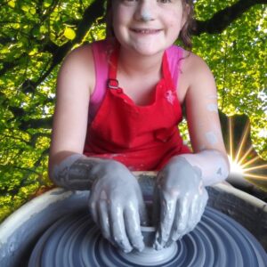 Student explores the pottery wheel during Clay and sculpture week.